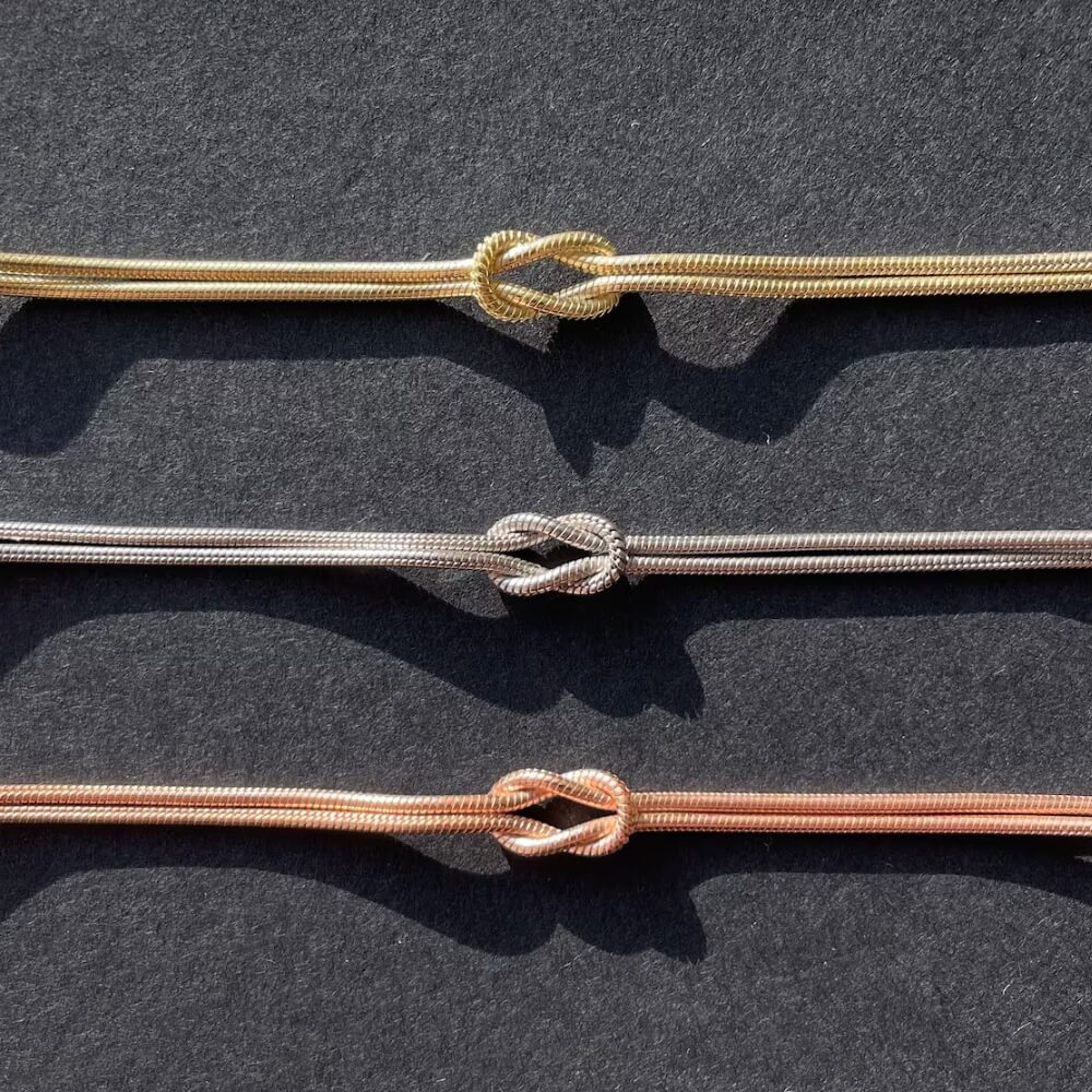 Drei Infinity-Knoten-Armbänder in Gold, Silber und Roségold – Zeitloses Design für stilbewusste Träger.