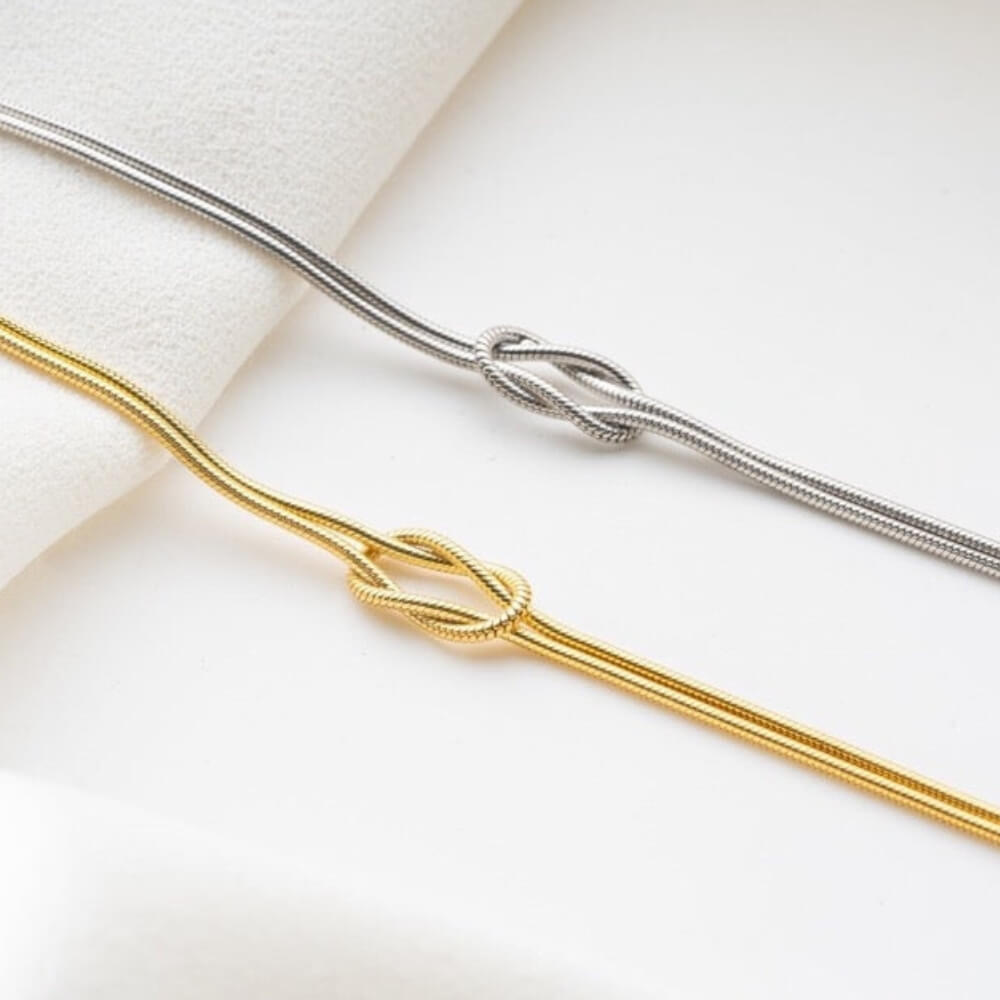 Gold- und silberne Armbänder mit Knoten-Design – Symbol für Verbundenheit und Freundschaft.