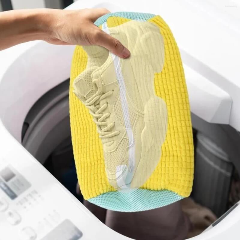 KickFresh Schuhwäschesack wird mit einem Schuh in eine Waschmaschine eingelegt.
